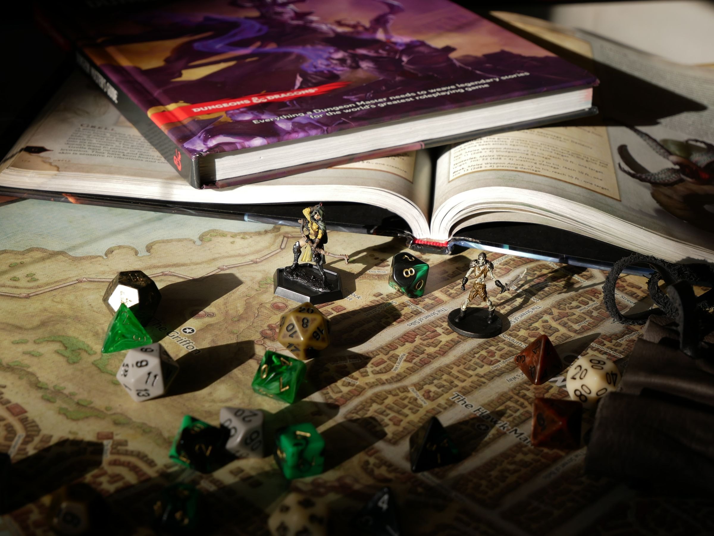Mesa de juego con manuales, dados y miniaturas sobre un mapa desplegado