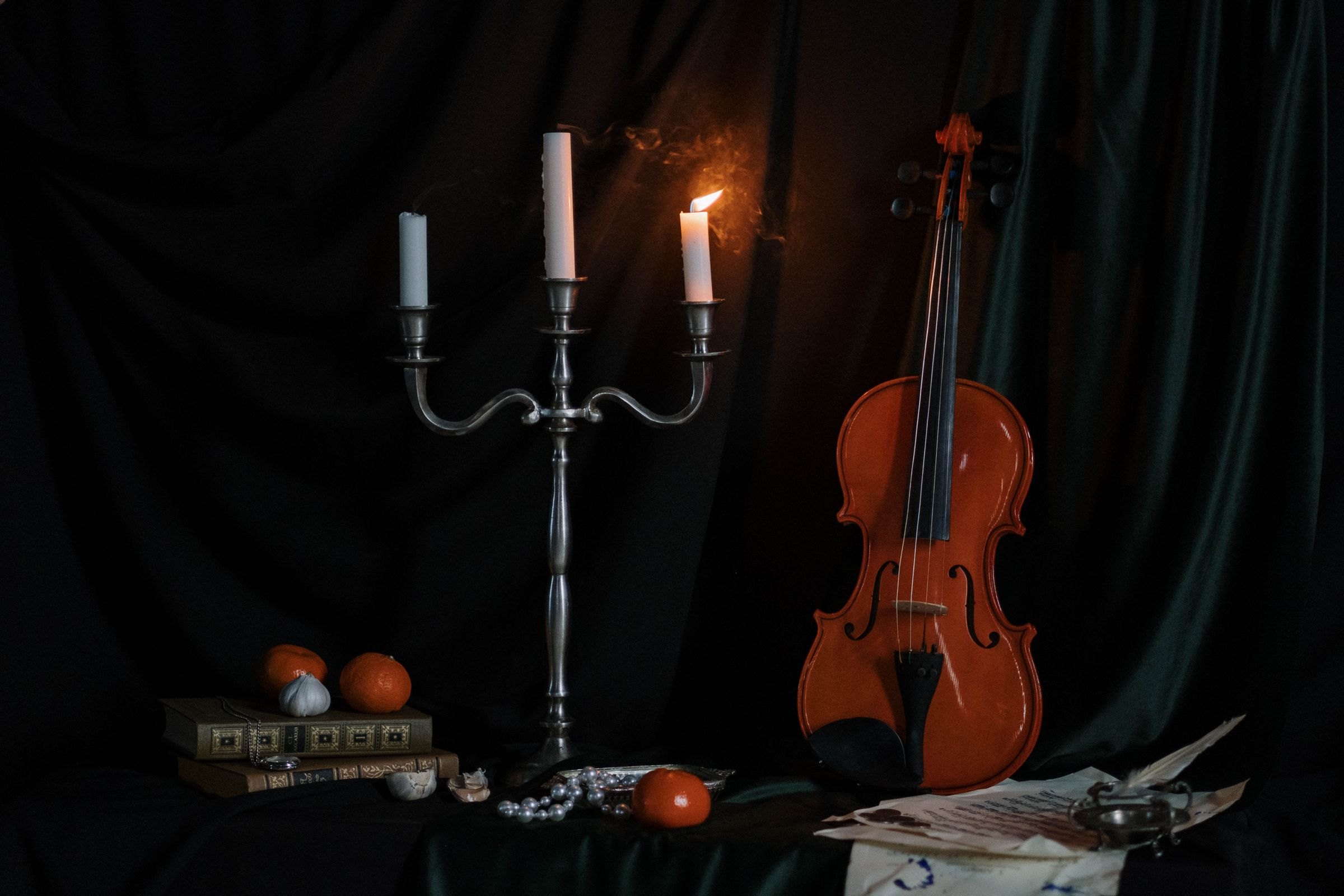 Bodegón con un violín, un candelabro y libros antiguos a la luz de las velas